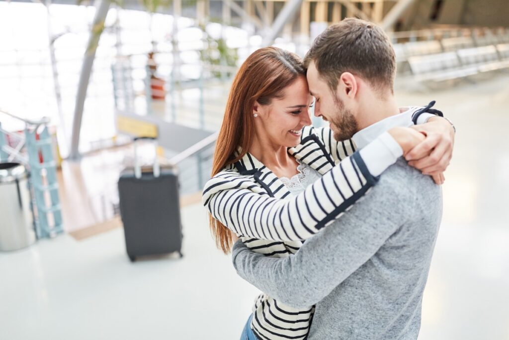 Un couple s'embrasse joyeusement lorsqu'ils se retrouvent à nouveau au terminal de l'aéroport