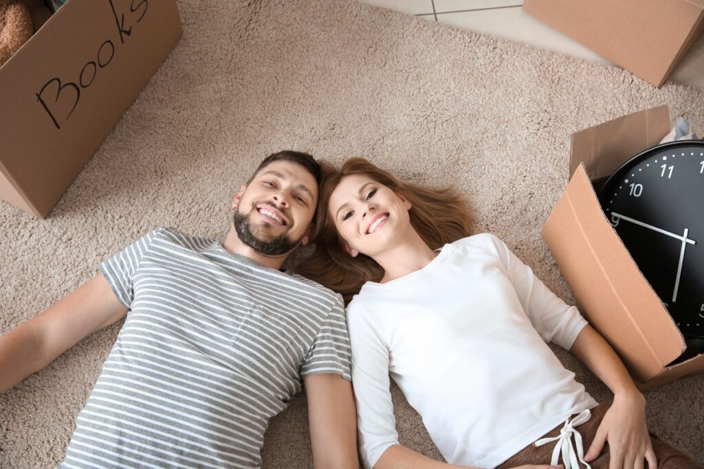 Couple allongé sur le sol à côté de cartons de déménagement