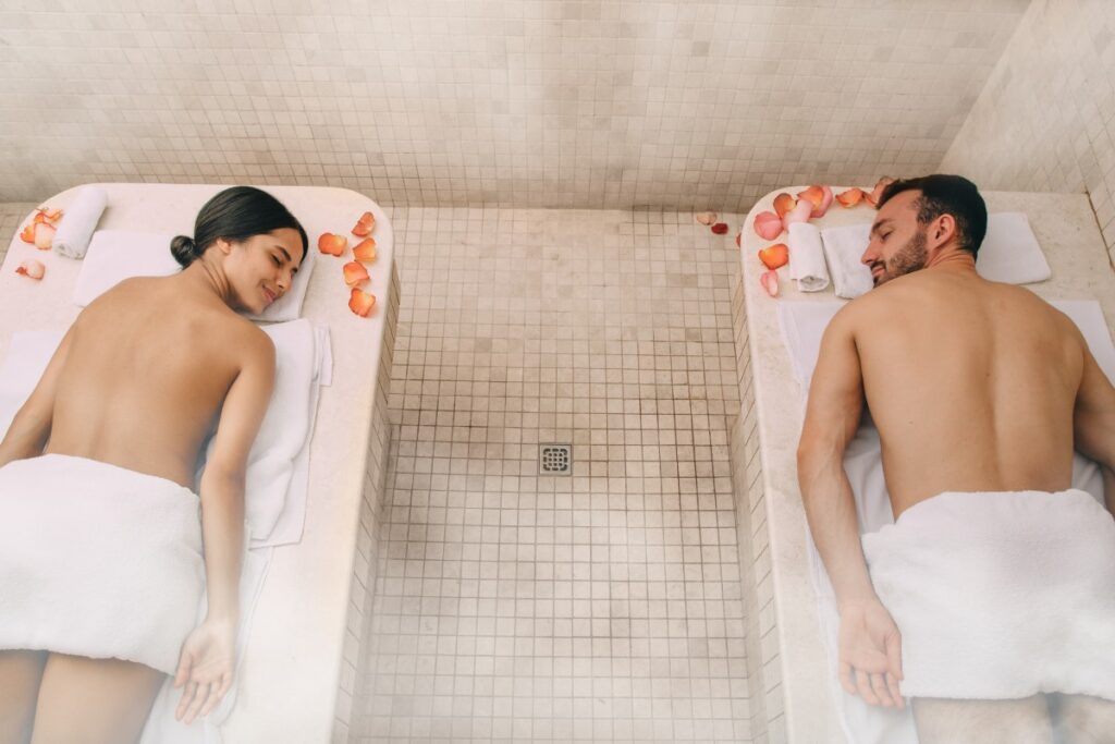 un couple allongé sur des lits profitant du hammam