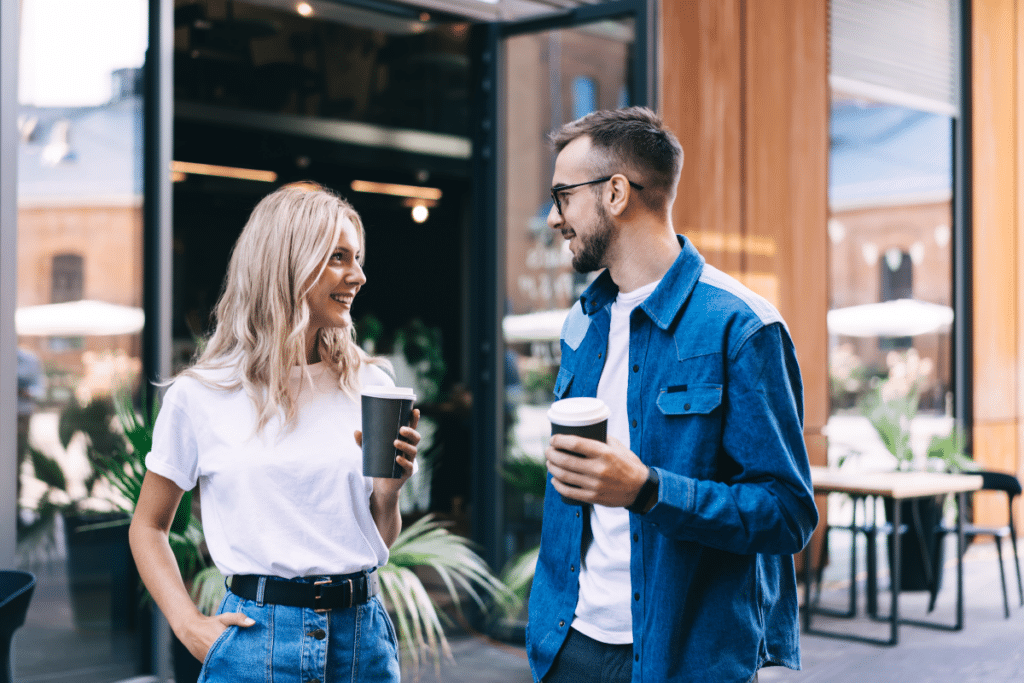 Jeune couple avec un café à emporter en train de discuter tout en souriant