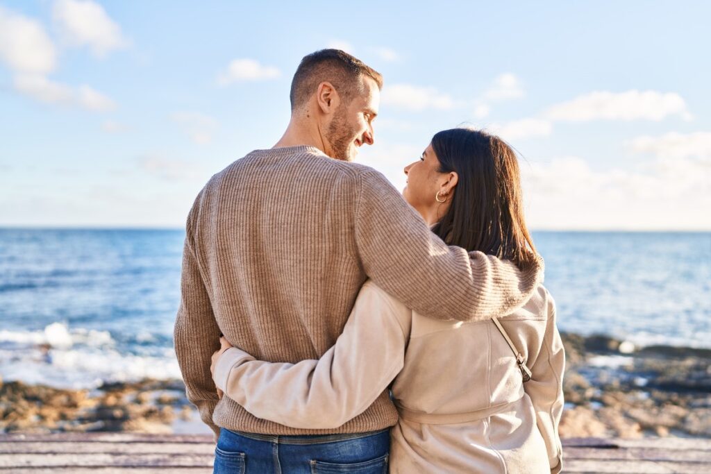Couple qui se regarde et s'embrasse devant la mer symbole de confiance
