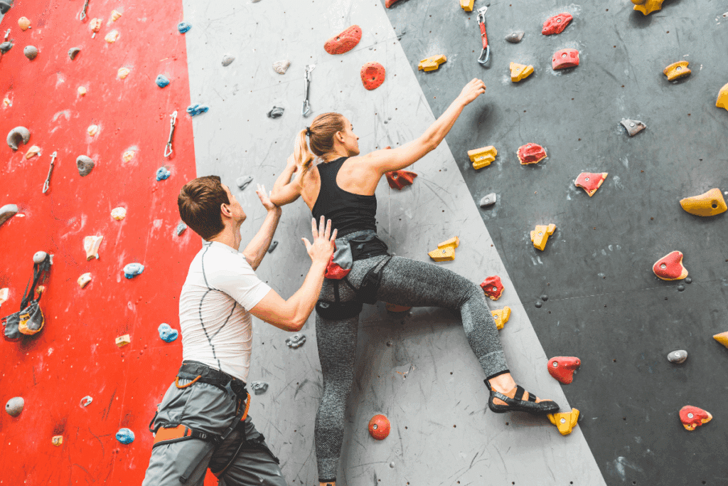 couple qui escalade un mur artificiel à l'intérieur