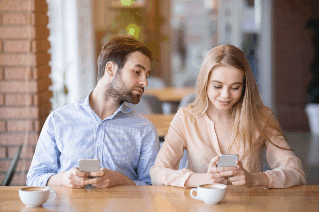 jeune homme jaloux regardant le téléphone de sa femme au café