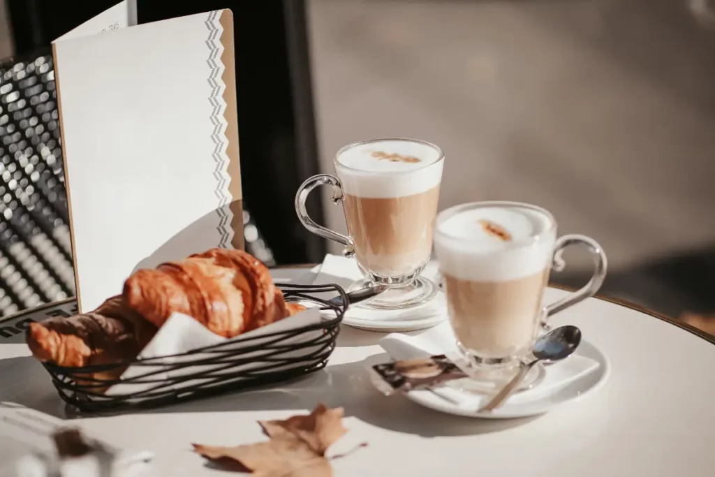 tasses de cappuccino, de croissants et de feuilles d'érable sur une table dans un café parisien