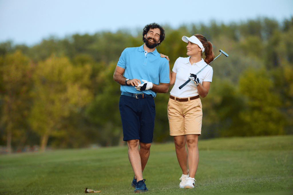 Joyeux couple de golfeurs s'amusant tout en jouant sur le terrain de golf