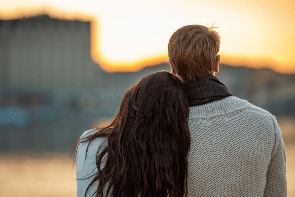 Jeune couple de derrière jouissant d'une vue paisible sur le coucher de soleil près de l'eau
